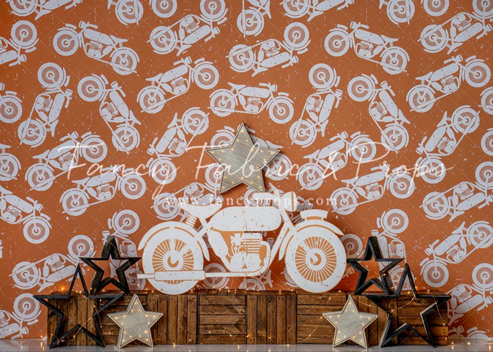 Orange wall with repeating white motorcycle pattern behind rustic wooden crates and star decorations.