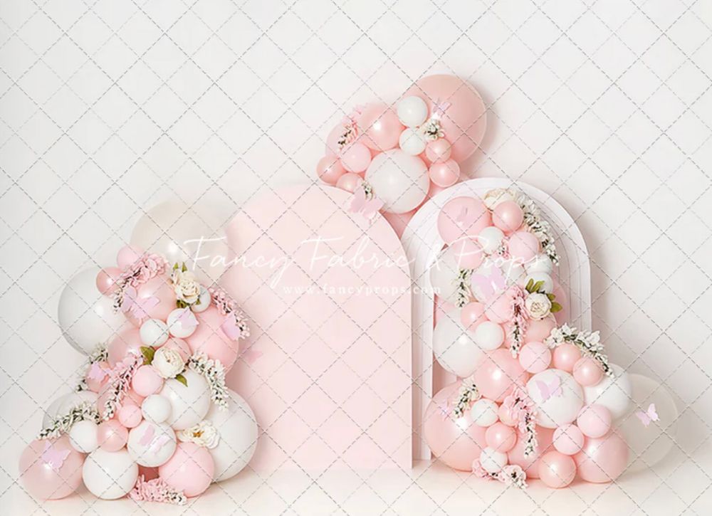 Pink heart shaped decorations adorned with delicate balloons and floral arrangements against a quilted background.