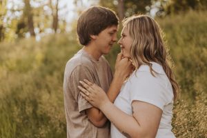 Intimate moment between couple in casual attire against natural outdoor setting.