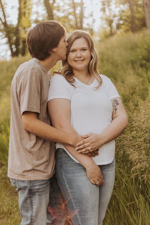 Tender moment shared between couple in casual wear during outdoor photo session.