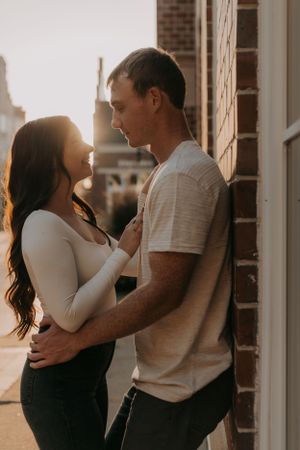 A tender embrace captured against brick architecture in warm sunset lighting.