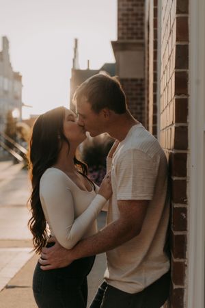 A romantic sunset kiss shared between a couple against an urban backdrop.