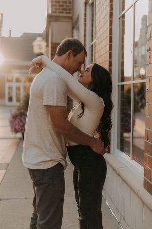 An intimate moment shared between a couple against a storefront at sunset.
