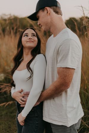 Romantic couple embracing in a field during golden hour.