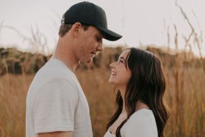 Intimate portrait of couple sharing tender moment in tall grass field at sunset.