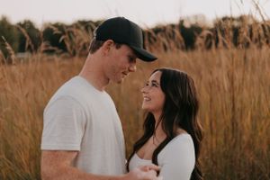 Romantic couple sharing intimate moment in field during golden hour.