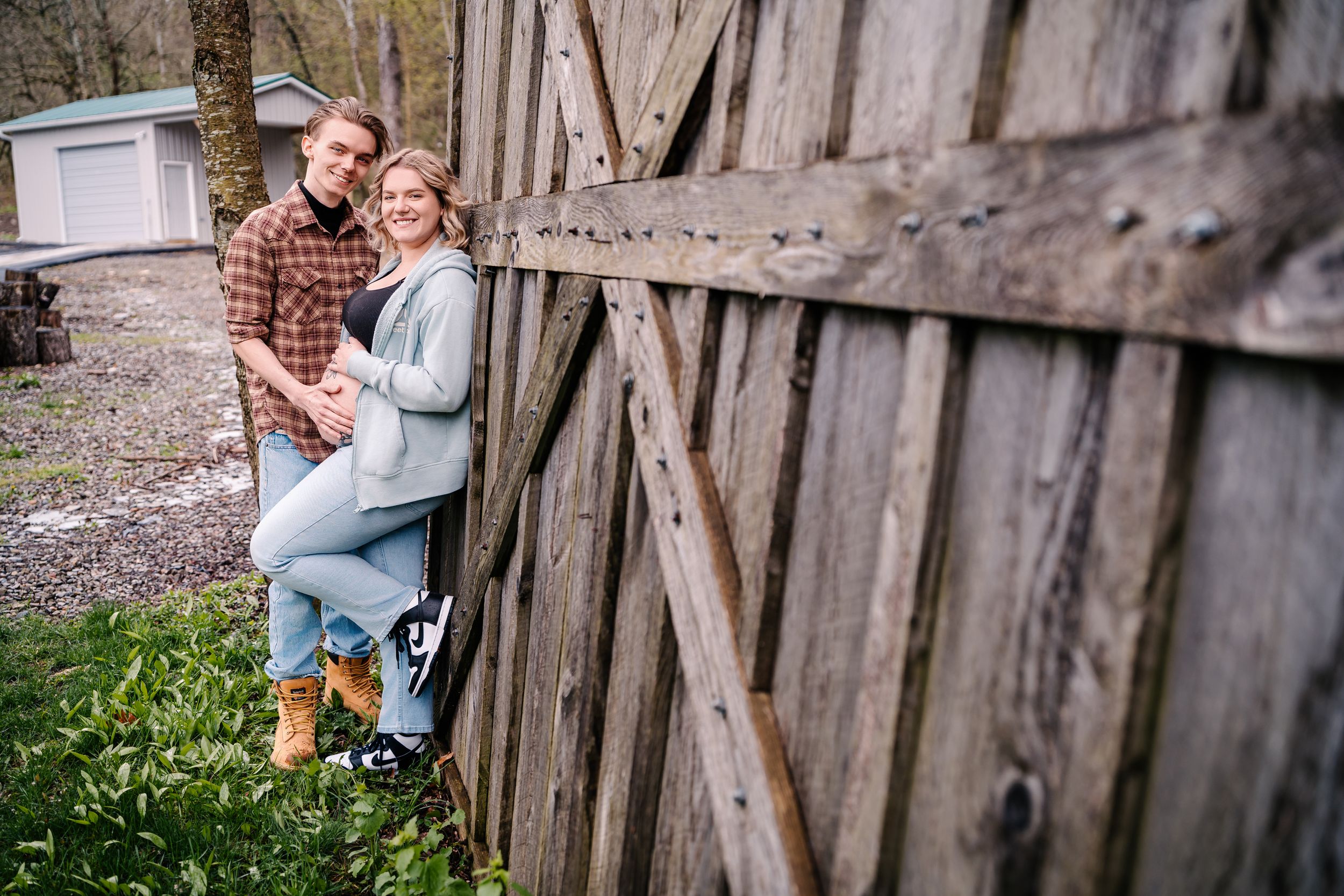 A casual outdoor portrait against a rustic wooden fence in casual attire.