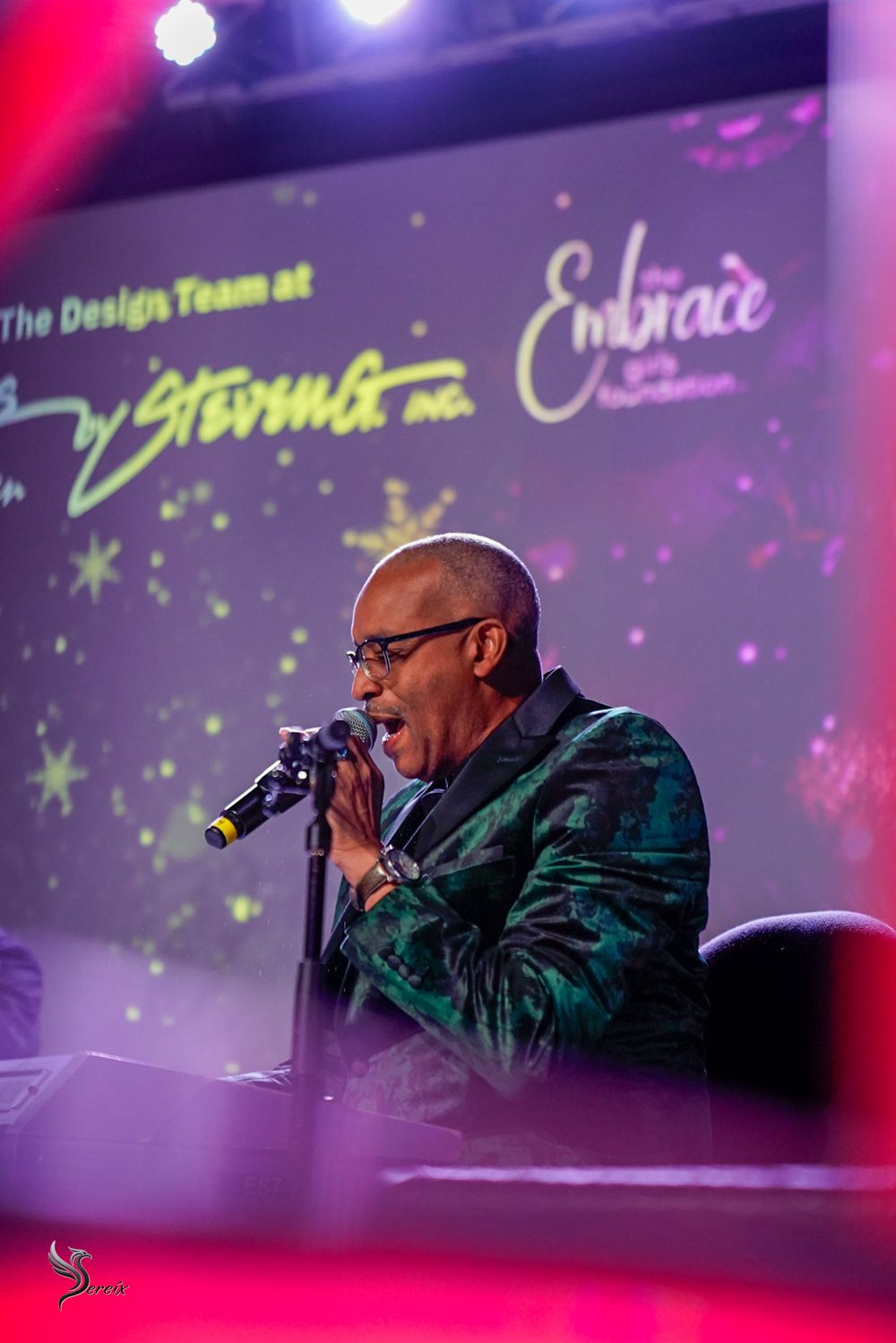 Musician performing live on stage under colorful concert lights, high-energy live music event photography by SRX Media Group