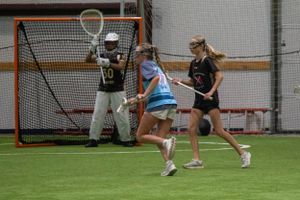 Lacrosse practice session with offensive player shooting on protected goalie.