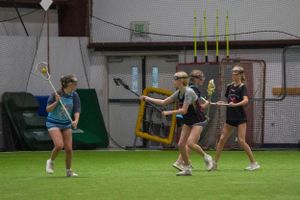 Players demonstrate lacrosse techniques during an indoor practice session.