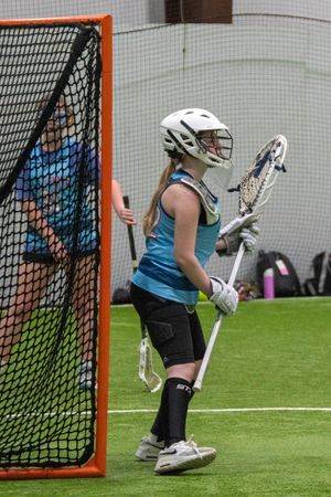 Lacrosse goalie in protective gear standing ready at the net during practice.