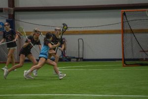Group of lacrosse players in action near the goal during an indoor practice session.