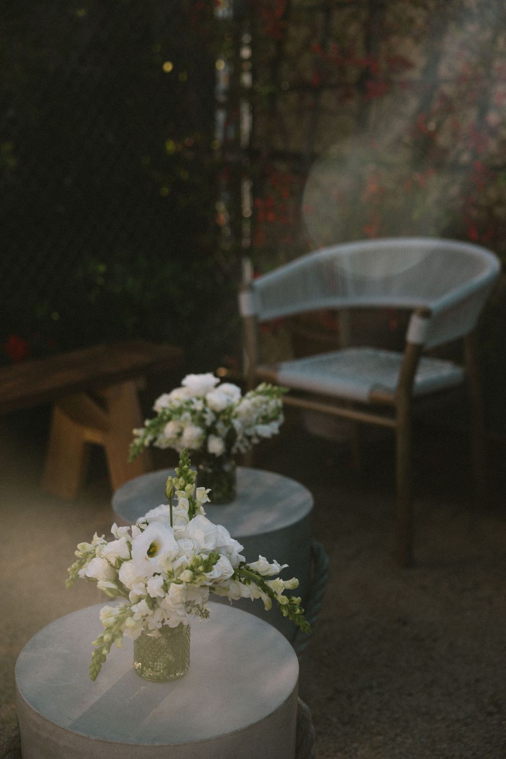 White floral arrangements in vases on round tables with modern seating.