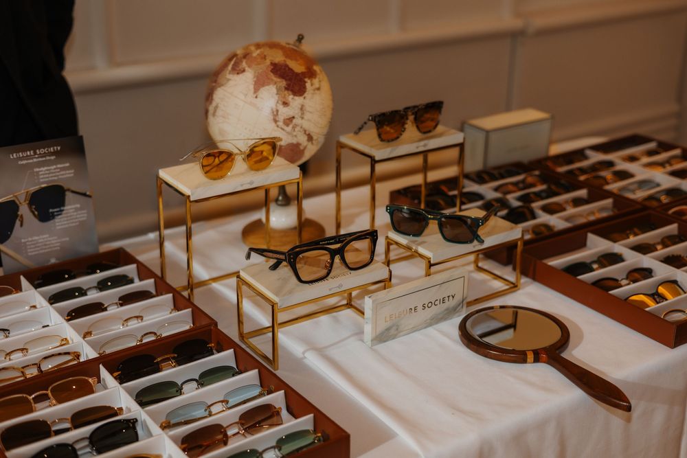 Elegant sunglasses display with gold stands, globe decor, and wooden trays showcasing luxury eyewear collection at a retail event.