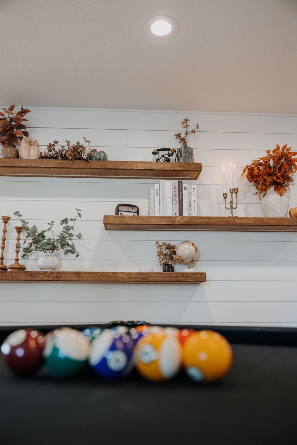 Rustic wooden floating shelves mounted on white shiplap wall with decorative items.