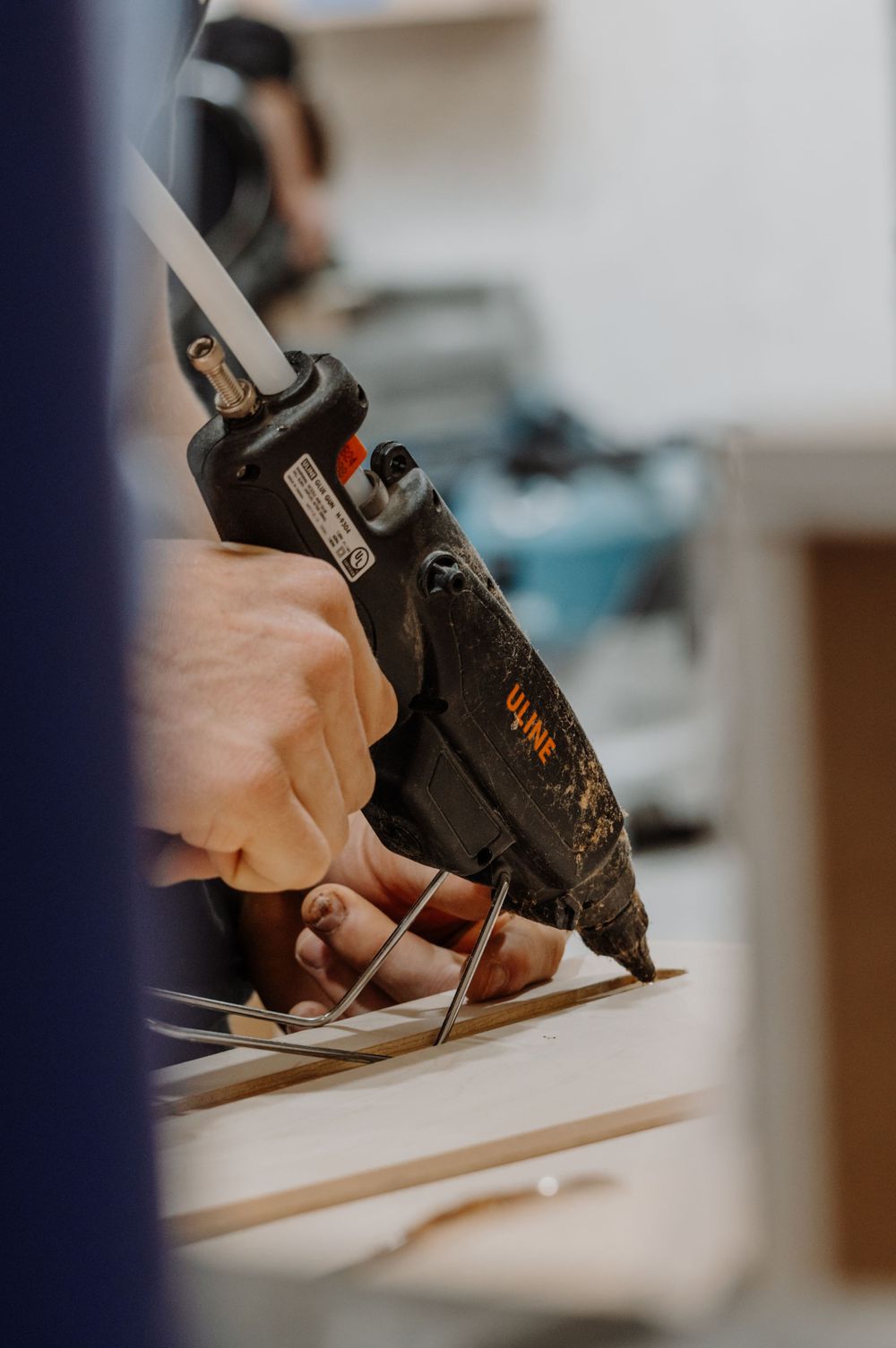 Close-up of hands using a power tool to secure wood pieces together.