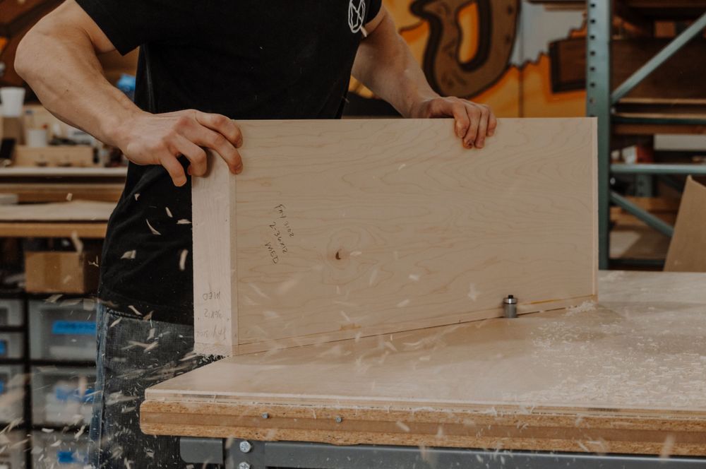 Craftsmen working with wood and tools in a workshop setting.