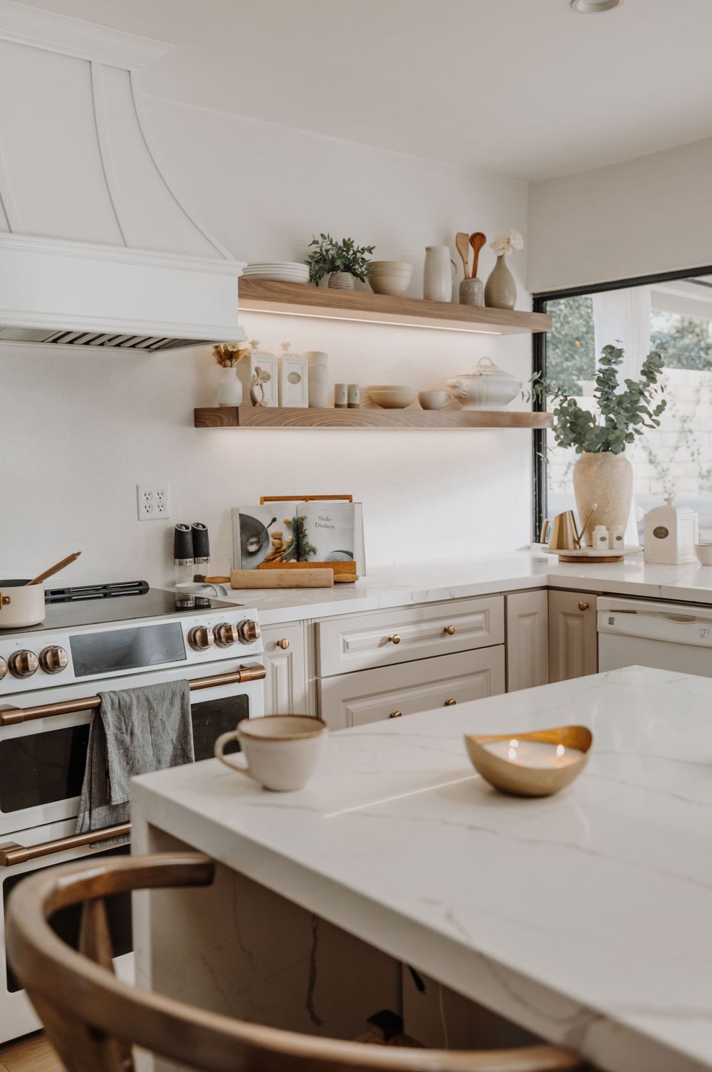 Modern white kitchen with wooden shelves and minimalist design.