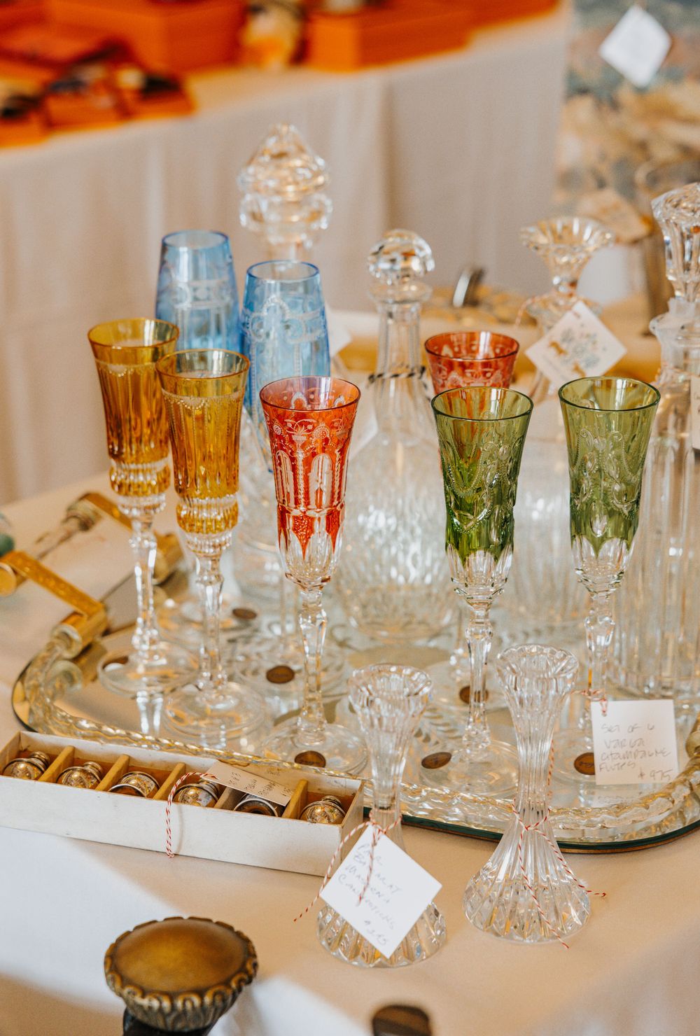Colorful crystal champagne flutes in blue, amber, red, and green displayed on a silver tray at an elegant event.