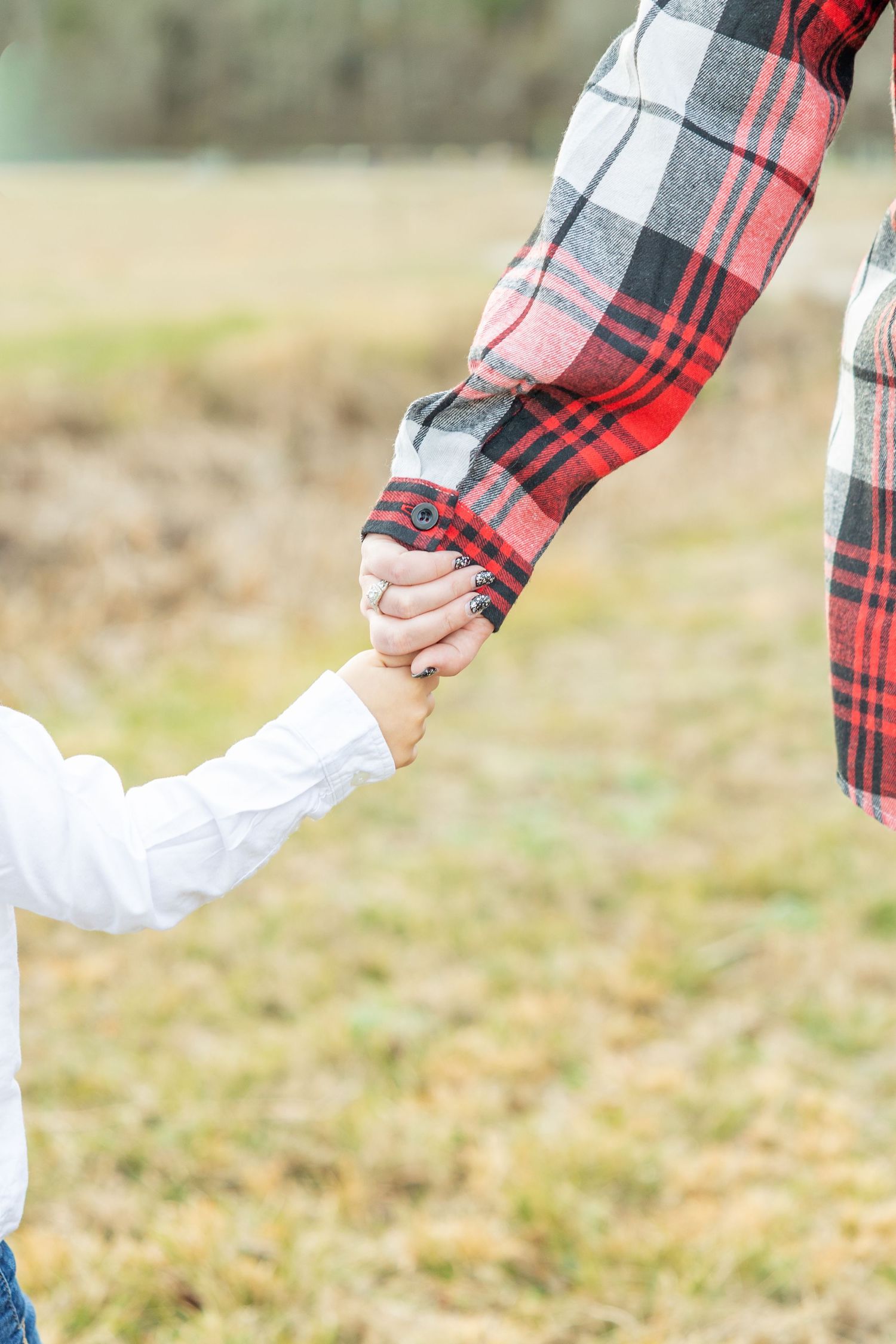 Hands reaching out wearing plaid flannel and white sleeves against autumn grass (Jacksonville, NC).