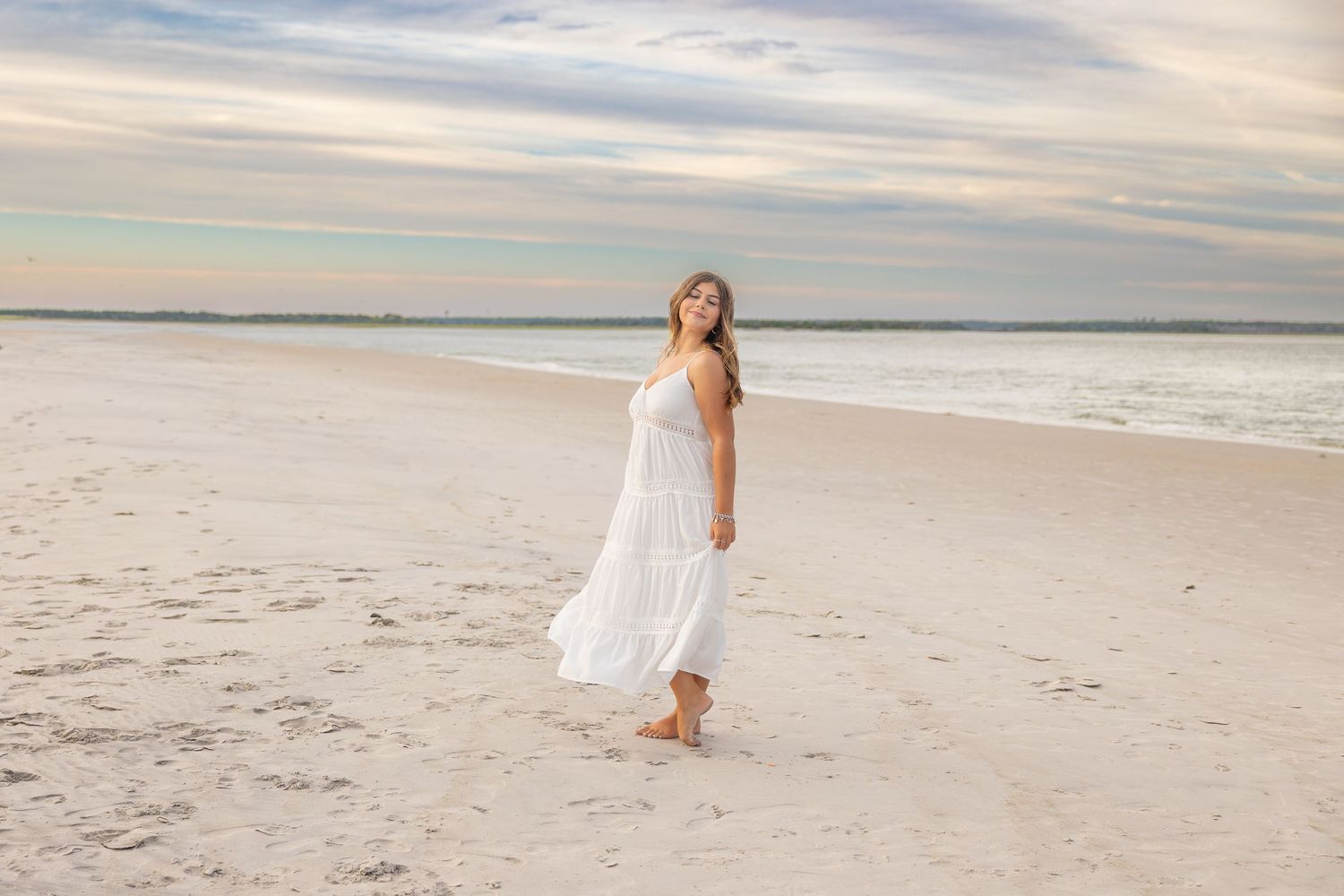A person in a flowing white dress walks along a peaceful beach at sunset (North Topsail, NC).