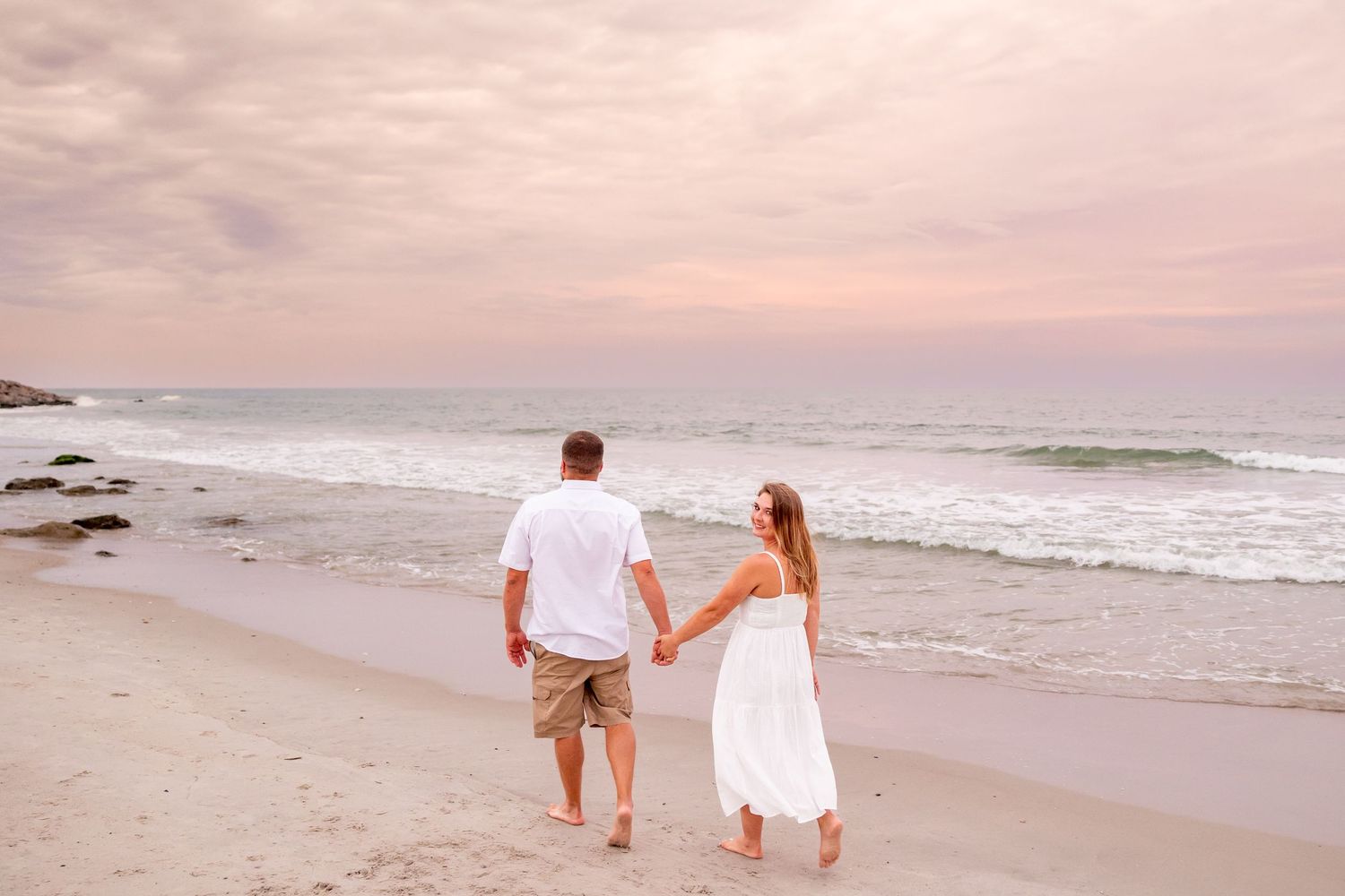 Couple walking hand in hand along a scenic beach during golden hour (Fort Fisher, NC).