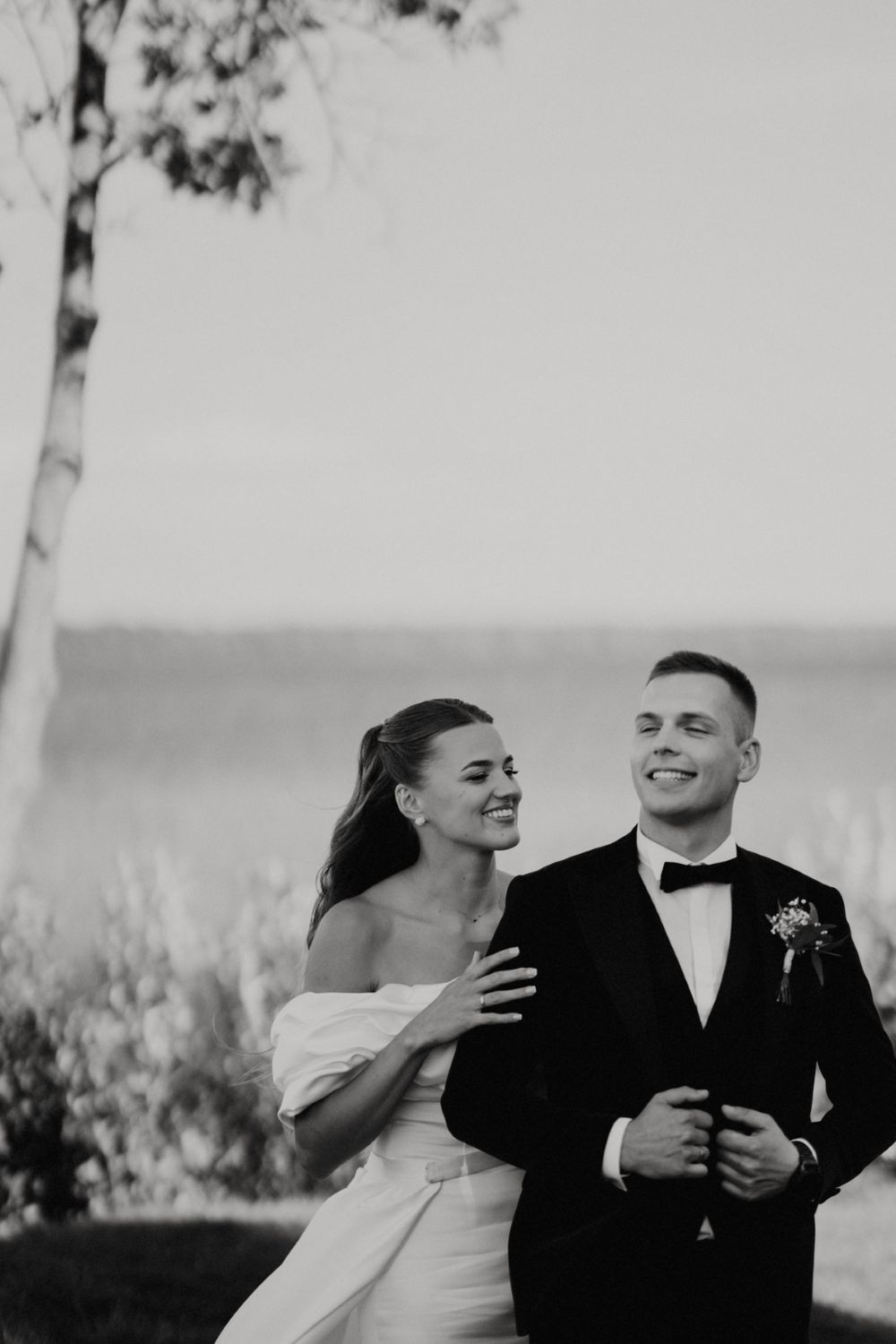 Joyful wedding couple sharing a candid moment outdoors in black and white.