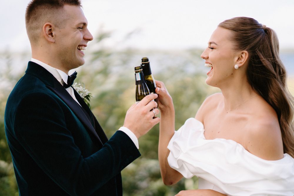 Happy couple toasting with miniature bottles during their wedding celebration.