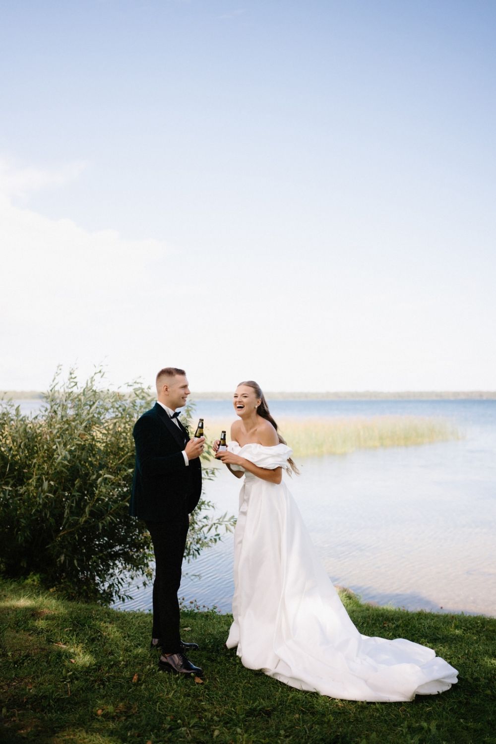 Newlyweds enjoying champagne together by a scenic waterfront.