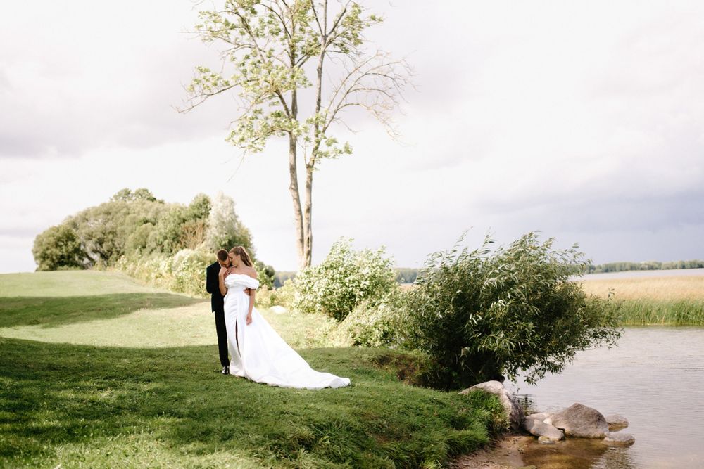 Romantic wedding couple silhouetted against a scenic outdoor landscape at sunset.