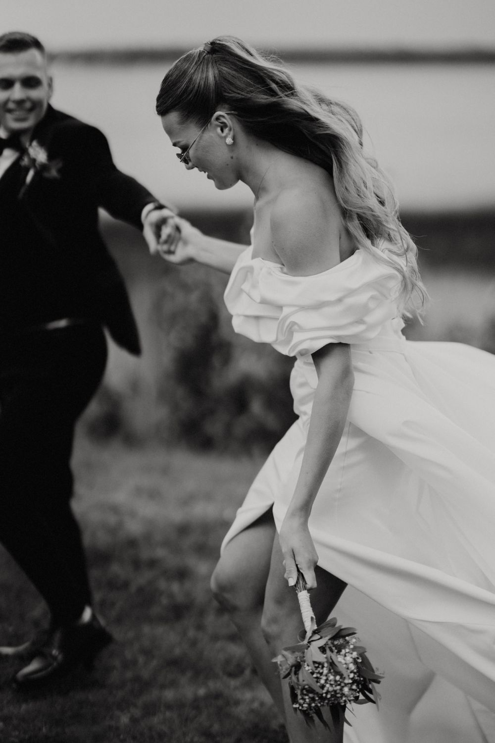 Black and white photo of flowing wedding dress movement in an outdoor setting.