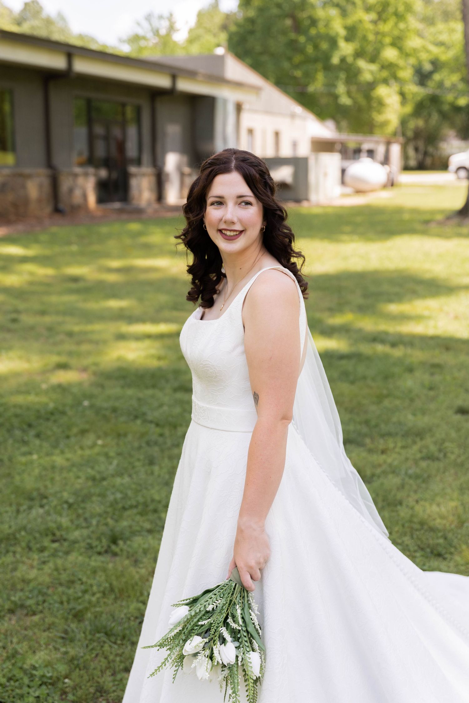 Person in a flowing white wedding dress twirls in a sunlit garden setting.