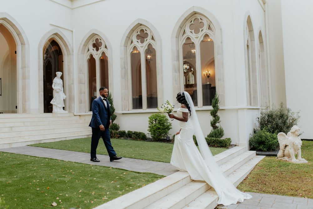 White stone wedding chapel with ornate Gothic architecture and lush garden surroundings.