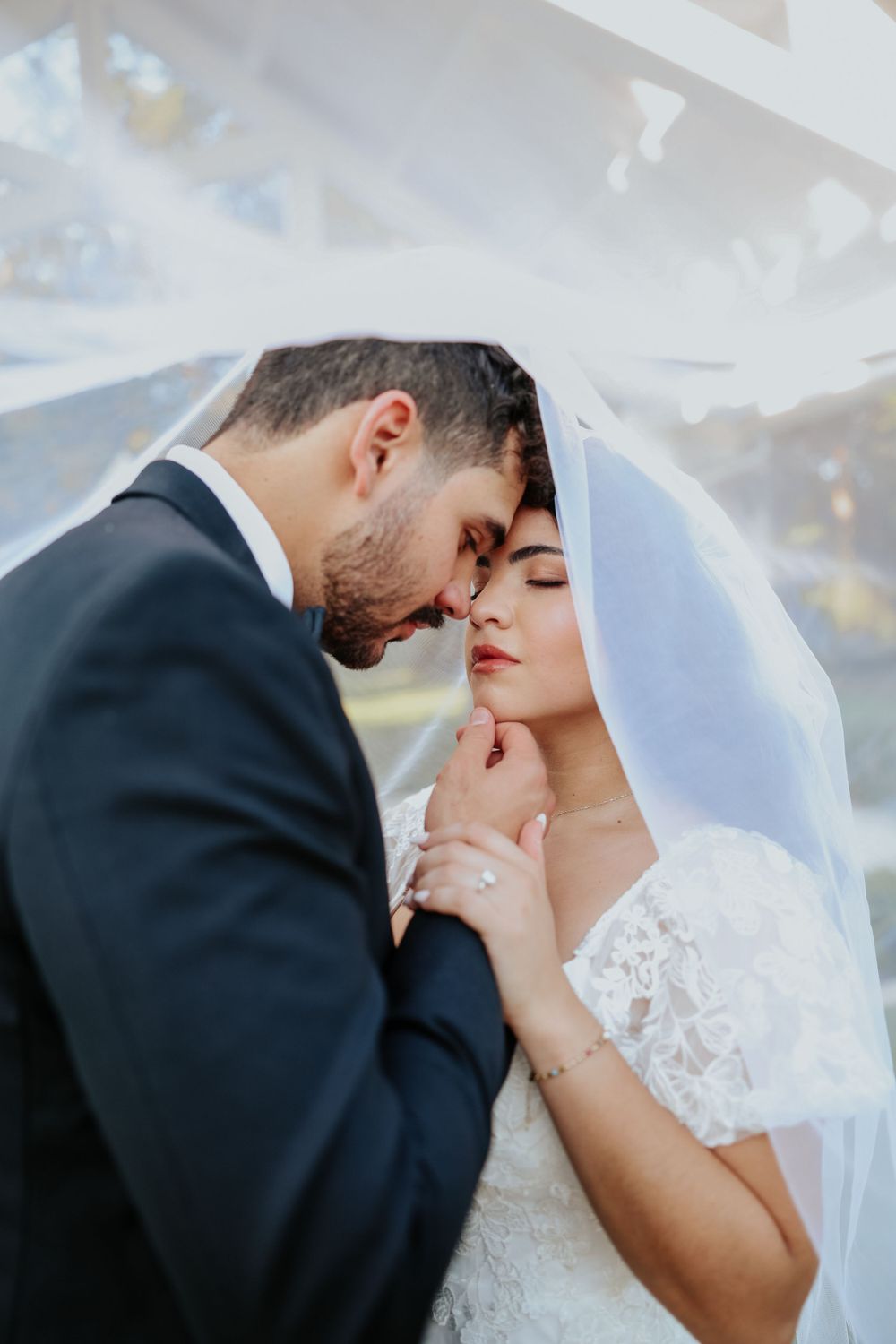 Intimate wedding moment captured under a flowing white veil.