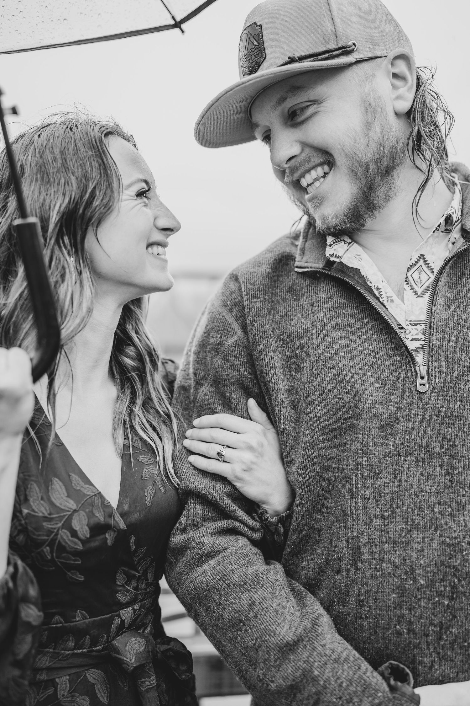 Black and white photo of a happy couple sharing an intimate moment, smiling together while wearing casual attire.