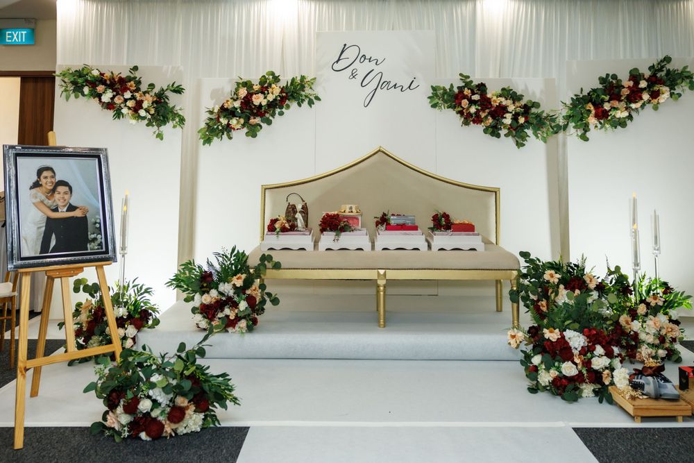 Elegant wedding stage with floral arches and gold-trimmed seating against a white backdrop.