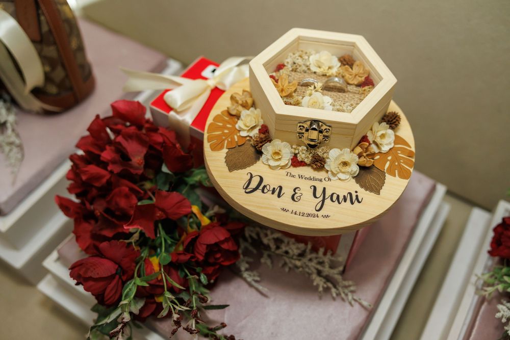 Hexagonal decorative box with "Don & Yani" text surrounded by red floral arrangements.