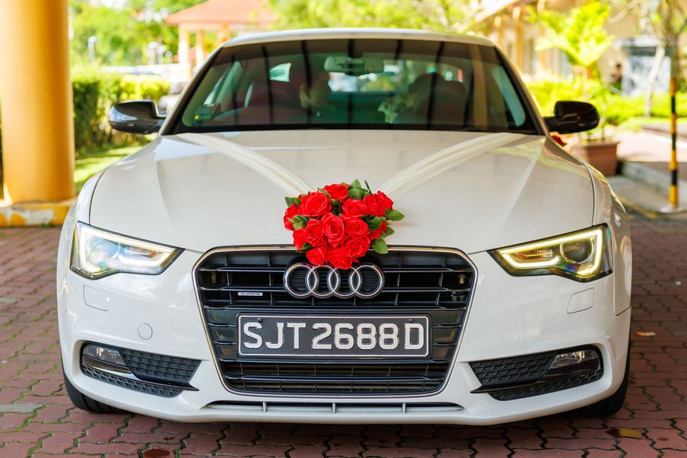 Front view of white Audi A5 decorated with red roses for a wedding ceremony.