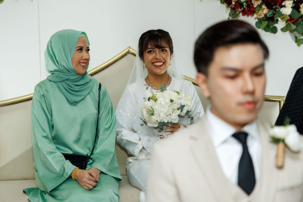 Wedding celebration with guests in formal attire seated on couch with floral decorations.