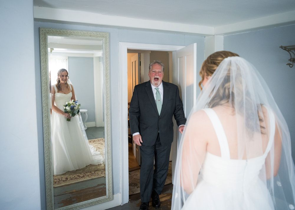 Emotional father seeing his daughter in her wedding dress and veil for the first time before the ceremony.