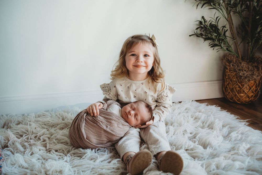 A collection of soft and dreamy lifestyle photos featuring siblings playing together on white bedding and blankets.