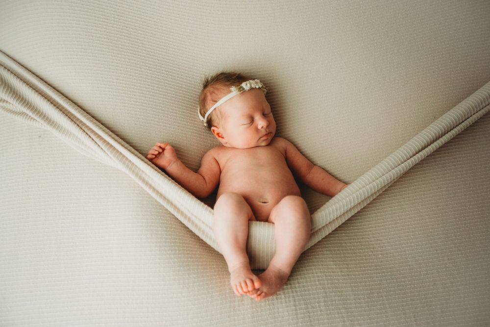 Baby feet and legs resting on white bedding in soft natural light.