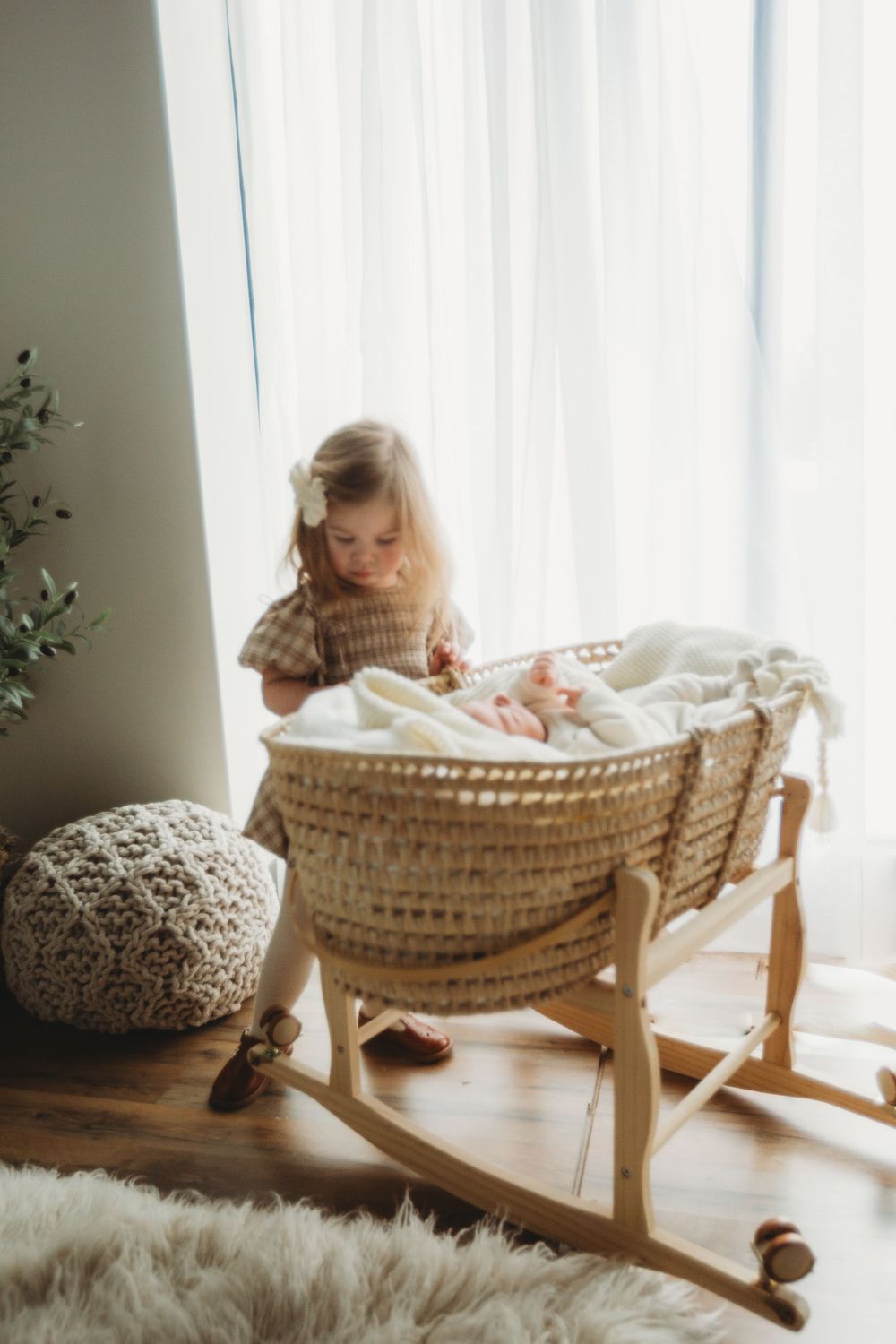 A series of photos showing a wooden rocking cradle with white bedding next to a window in warm natural light.