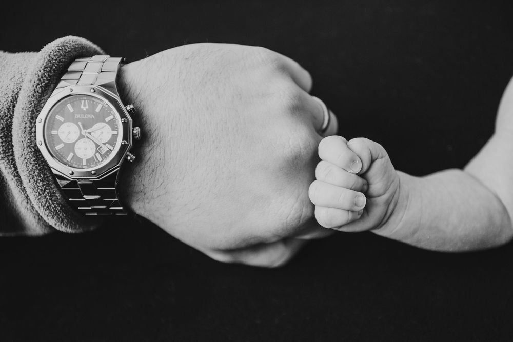 A series of black and white photos showing hands exchanging a silver wristwatch in different angles.