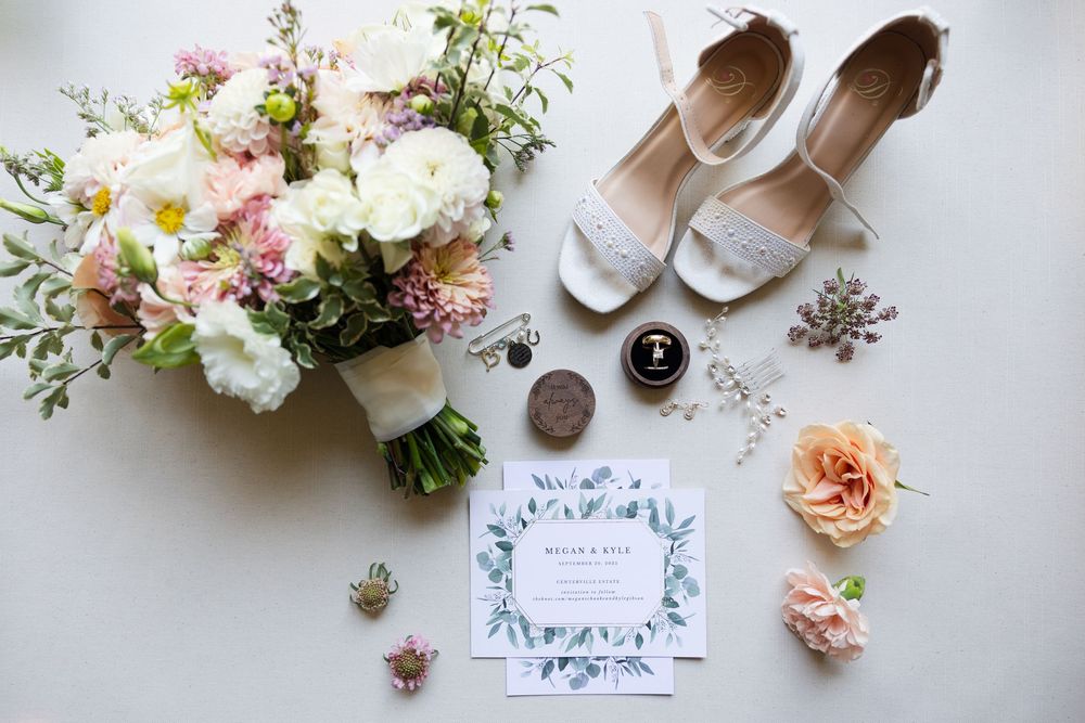 Wedding detail flatlay featuring delicate floral bouquet, invitation and bridal accessories.