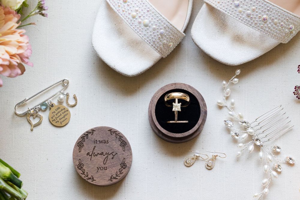 Wedding accessories including lace details, jewelry, and personalized ring boxes on white surface.
