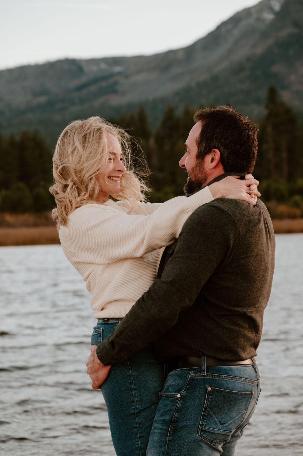 Romantic couple embraces by a mountain lake in a series of candid moments at sunset.