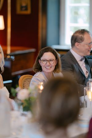 Guests enjoying a formal dinner event in an elegant dining room with warm lighting and candlelit ambiance.