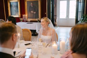 A candlelit dinner table set with elegant glassware and white candles in an ornate dining room with vintage portraits.