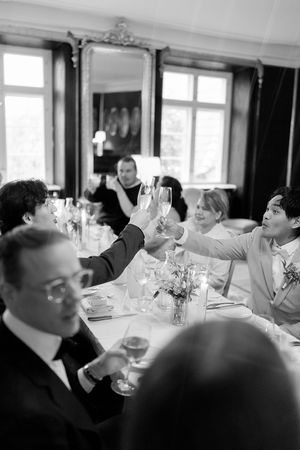 Black and white photo of guests laughing and socializing at an elegant dining event with formal table settings.